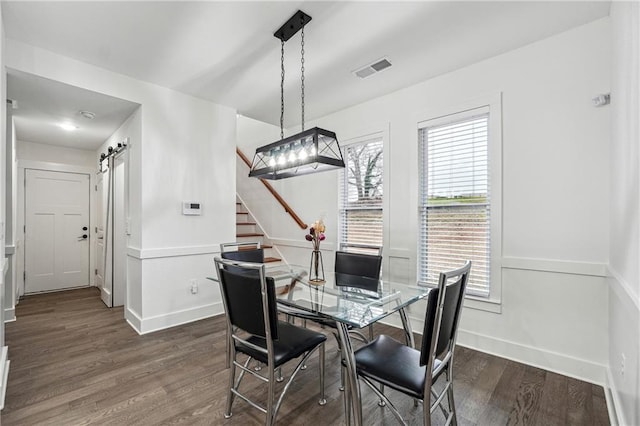 dining room featuring visible vents, baseboards, stairs, dark wood-type flooring, and a barn door