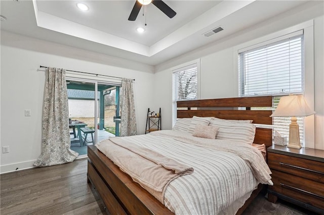 bedroom featuring visible vents, access to outside, wood finished floors, baseboards, and a raised ceiling