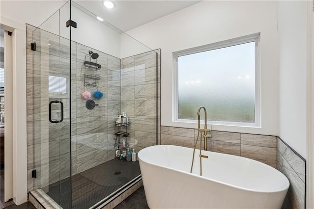 bathroom with a shower stall, recessed lighting, tile walls, and a freestanding bath