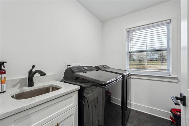 washroom with a sink, baseboards, cabinet space, and separate washer and dryer