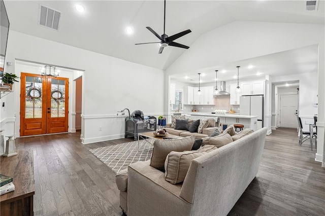 living area with dark wood-style floors, visible vents, ceiling fan with notable chandelier, and high vaulted ceiling