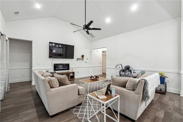 living area featuring visible vents, high vaulted ceiling, a glass covered fireplace, wood finished floors, and ceiling fan