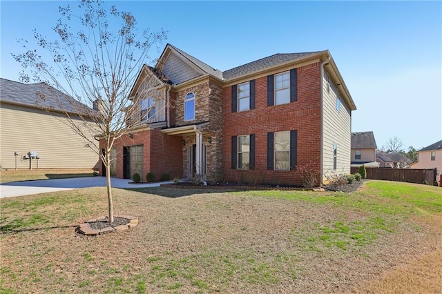 view of front of property with a front yard, concrete driveway, brick siding, and fence