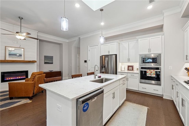 kitchen with white cabinetry, sink, stainless steel appliances, and a center island with sink