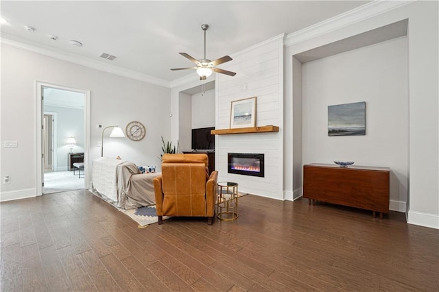 living room with crown molding, a large fireplace, dark hardwood / wood-style flooring, and ceiling fan