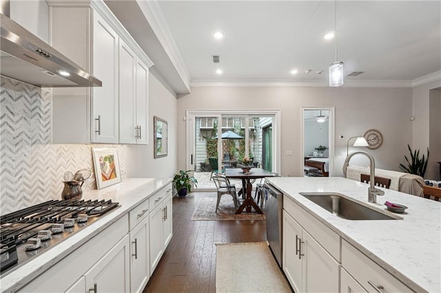 kitchen with wall chimney exhaust hood, sink, white cabinetry, appliances with stainless steel finishes, and light stone countertops
