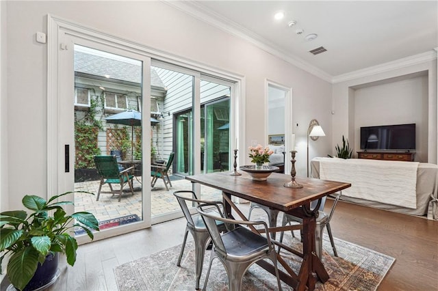 dining space with hardwood / wood-style flooring and ornamental molding