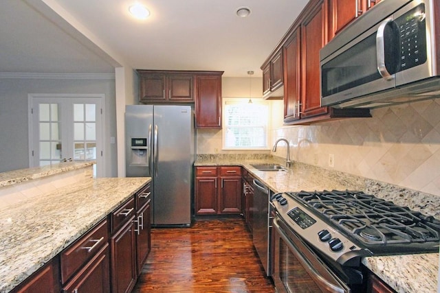 kitchen with stainless steel appliances, a sink, and light stone countertops