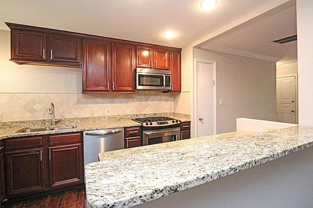 kitchen featuring light stone counters, decorative backsplash, appliances with stainless steel finishes, ornamental molding, and a sink