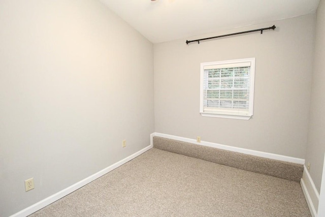 empty room with carpet flooring, vaulted ceiling, and baseboards