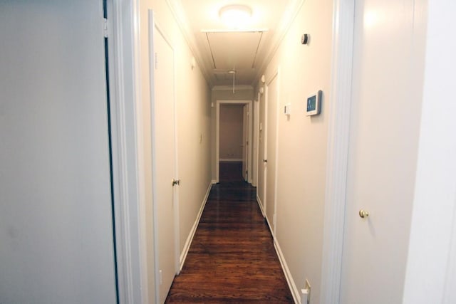 corridor with dark wood-style floors, attic access, ornamental molding, and baseboards