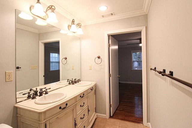 bathroom featuring crown molding, a healthy amount of sunlight, visible vents, and a sink