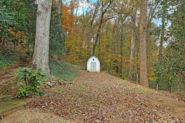 view of yard featuring a shed, a wooded view, and an outdoor structure