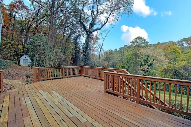 deck featuring an outbuilding, a wooded view, and a shed