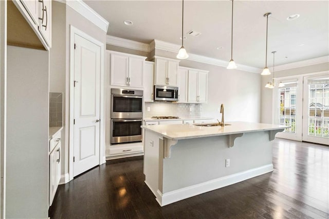 kitchen with dark wood finished floors, stainless steel appliances, backsplash, and a sink