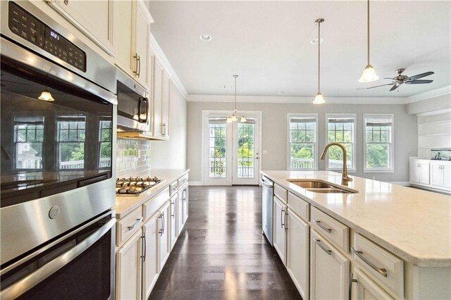 kitchen with dark wood-style floors, a sink, stainless steel appliances, decorative light fixtures, and ornamental molding