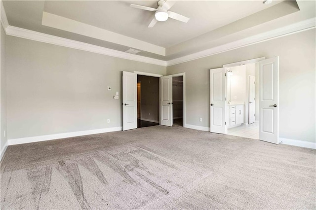 unfurnished bedroom featuring a raised ceiling, ornamental molding, and carpet flooring