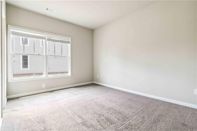 carpeted spare room with visible vents and baseboards