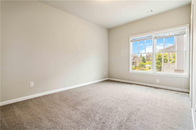 spare room featuring carpet floors, visible vents, and baseboards