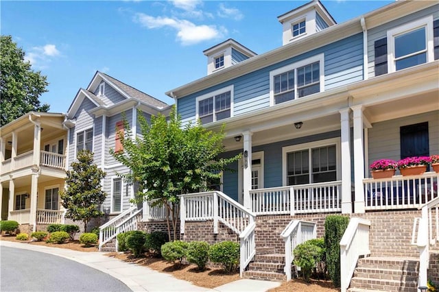 townhome / multi-family property featuring stairs and covered porch