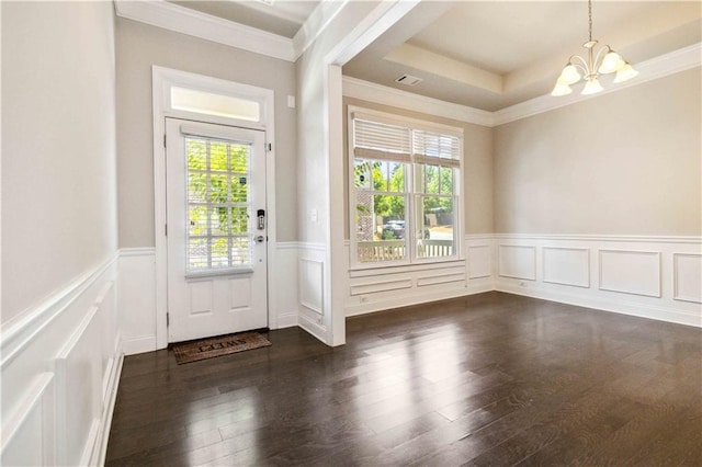 doorway to outside featuring a wealth of natural light, ornamental molding, a wainscoted wall, and a notable chandelier