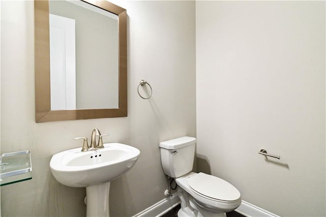 bathroom with toilet, a sink, and baseboards
