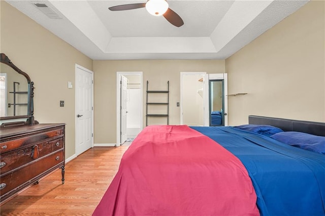 539 Mcgill Park Ave NE, Atlanta, GA 30312 - bedroom with wood finished floors, a raised ceiling, baseboards, a ceiling fan, and ensuite bathroom