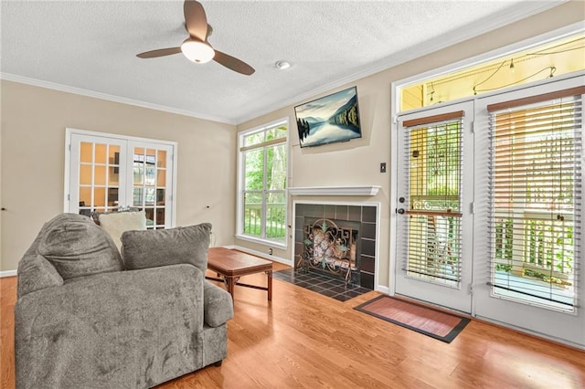 539 Mcgill Park Ave NE, Atlanta, GA 30312 - living room with crown molding, a ceiling fan, wood finished floors, a textured ceiling, and a tile fireplace