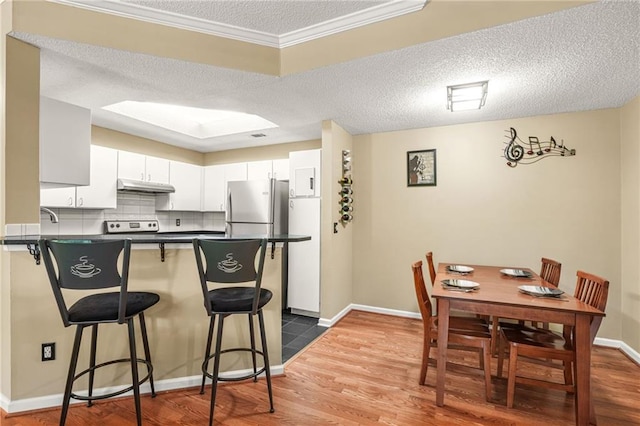 539 Mcgill Park Ave NE, Atlanta, GA 30312 - kitchen featuring under cabinet range hood, a peninsula, dark countertops, a textured ceiling, and dark wood-style floors