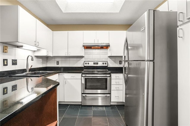 539 Mcgill Park Ave NE, Atlanta, GA 30312 - kitchen featuring appliances with stainless steel finishes, under cabinet range hood, a sink, tasteful backsplash, and white cabinetry