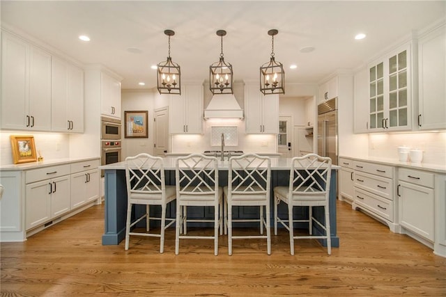 kitchen featuring white cabinetry, a center island with sink, and pendant lighting