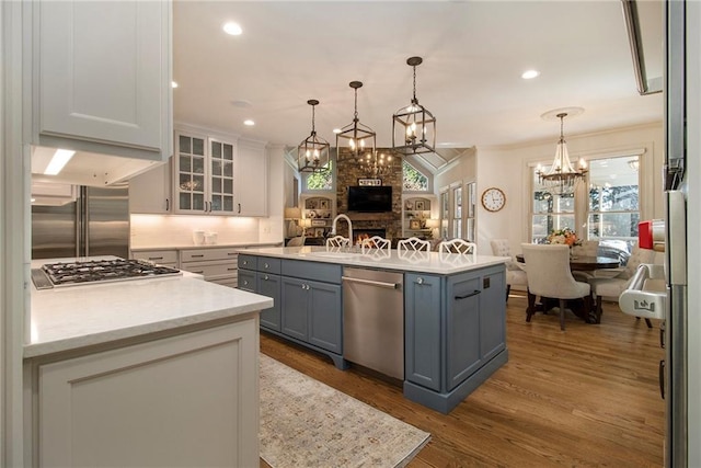 kitchen with gray cabinetry, a center island, decorative light fixtures, white cabinets, and appliances with stainless steel finishes