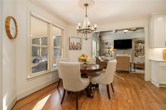 dining space with ceiling fan with notable chandelier, light hardwood / wood-style floors, built in features, and ornamental molding