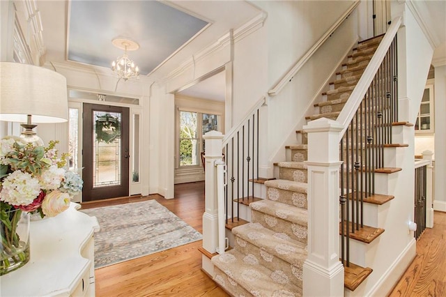 foyer with an inviting chandelier, light hardwood / wood-style flooring, and crown molding