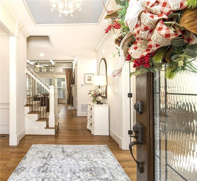 foyer featuring crown molding, wood-type flooring, and ceiling fan with notable chandelier