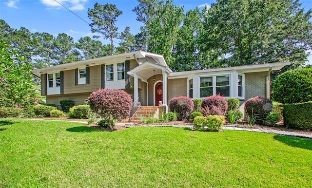 tri-level home with brick siding and a front yard