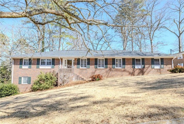 ranch-style home with brick siding, a front yard, and cooling unit