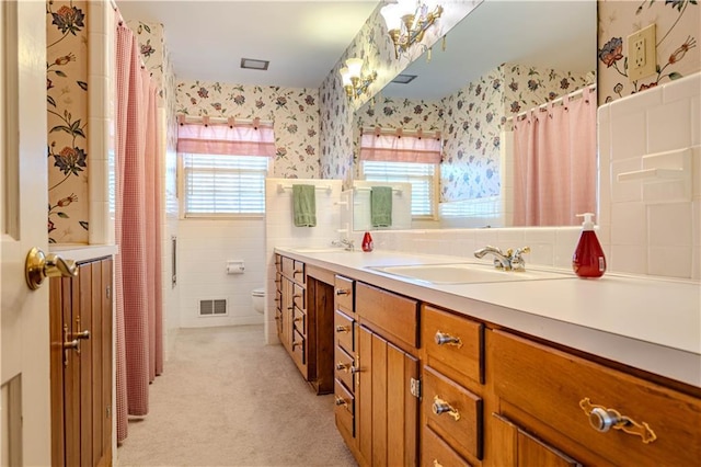 full bathroom with plenty of natural light, visible vents, a sink, and wallpapered walls