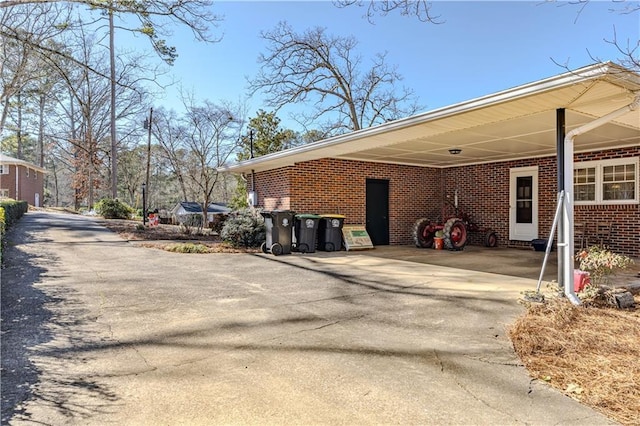 view of property exterior featuring driveway, an attached carport, and brick siding