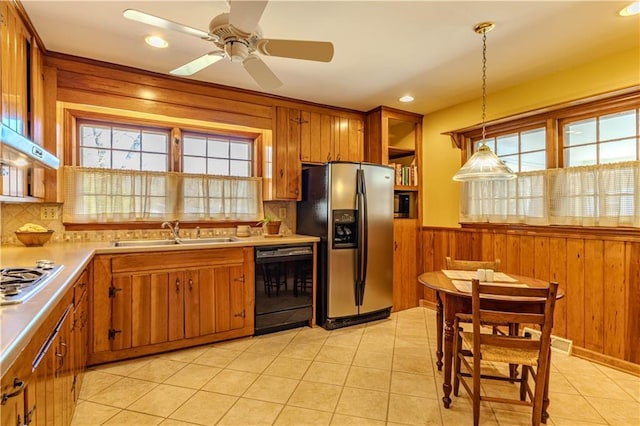 kitchen with brown cabinetry, decorative light fixtures, stainless steel appliances, light countertops, and a sink