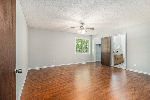 7002 Spout Springs Rd, Flowery Branch, GA 30542 - unfurnished bedroom with dark wood-style flooring, a textured ceiling, connected bathroom, and a ceiling fan