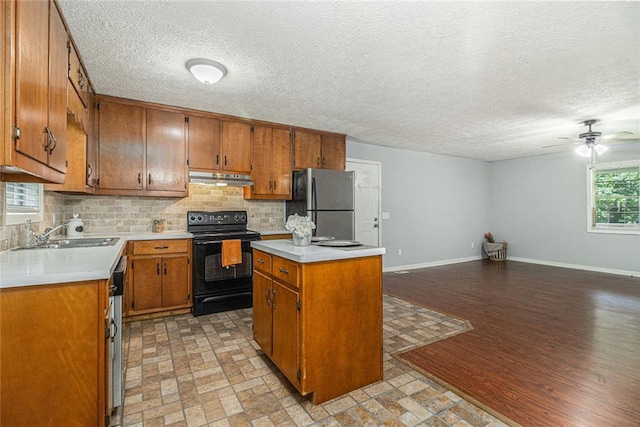 7002 Spout Springs Rd, Flowery Branch, GA 30542 - kitchen featuring black range with electric cooktop, freestanding refrigerator, under cabinet range hood, decorative backsplash, and brown cabinets