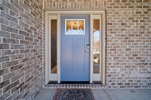 view of exterior entry featuring brick siding