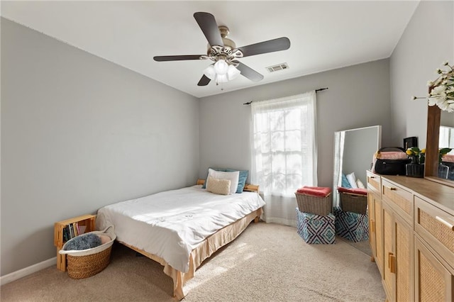 bedroom featuring baseboards, visible vents, light colored carpet, and a ceiling fan