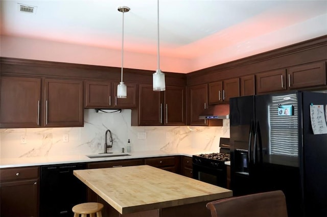 kitchen with dark brown cabinetry, black appliances, under cabinet range hood, visible vents, and a sink