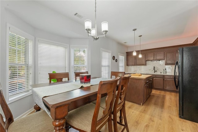 dining room with visible vents, light wood-type flooring, and a notable chandelier
