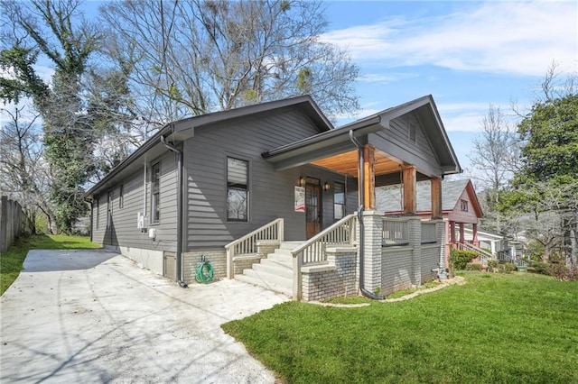 view of front of property featuring driveway, covered porch, and a front lawn