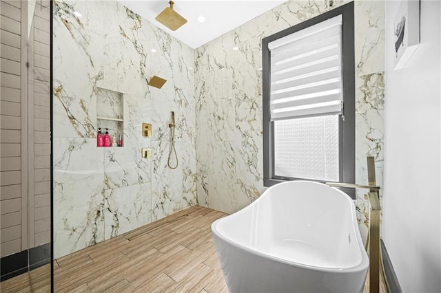 bathroom featuring a marble finish shower, a freestanding bath, and wood finished floors