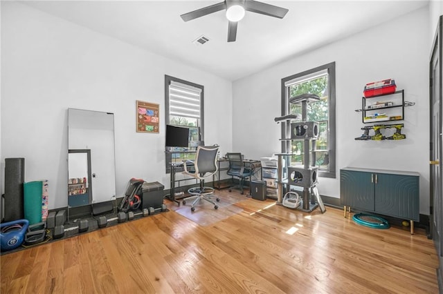 workout area with visible vents, ceiling fan, and wood finished floors