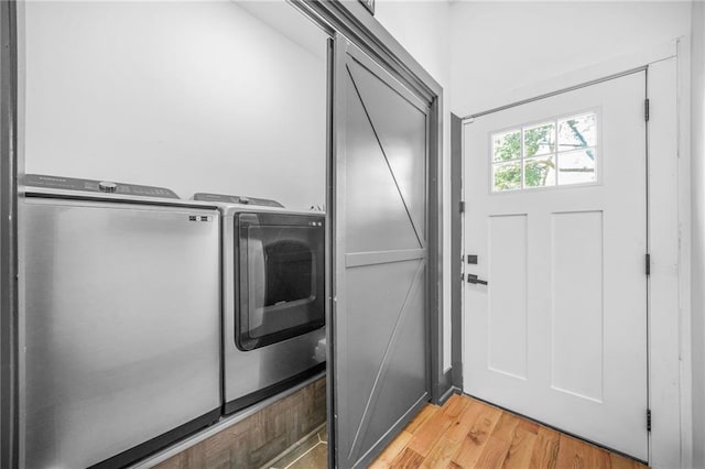 laundry room with laundry area, light wood finished floors, and washer and clothes dryer